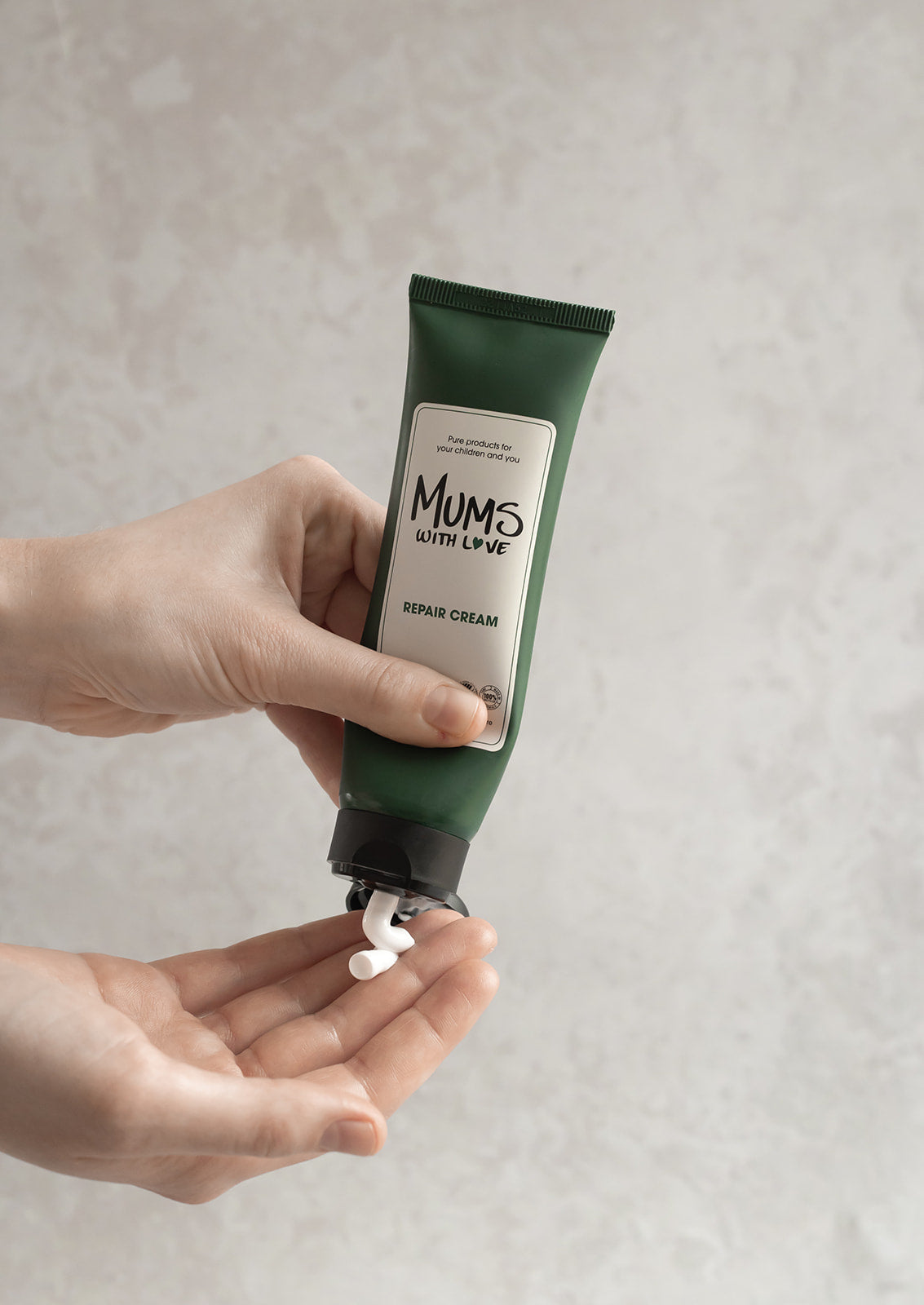 Billedet viser den certificeret, veganske og parfumefri Repair Cream fra MUMS WITH LOVE blive smurt ud i en hånd.